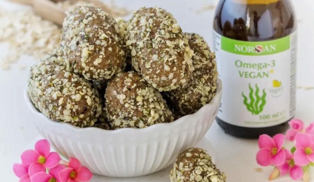 Foto di praline a forma di ovetto in una ciotola, di fianco una bottiglia di NORSAN Omega-3 Vegano